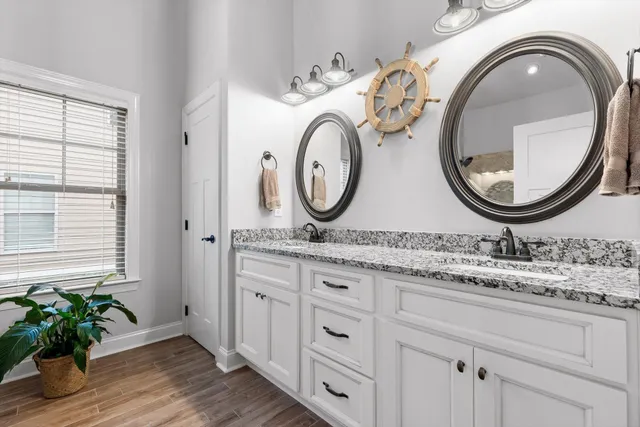 a bathroom with a granite countertop double vanity sink and mirror