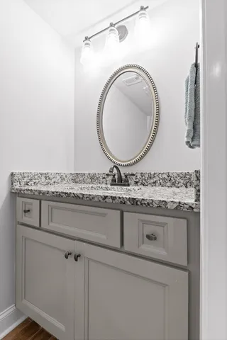 a bathroom with a granite countertop sink a mirror and vanity