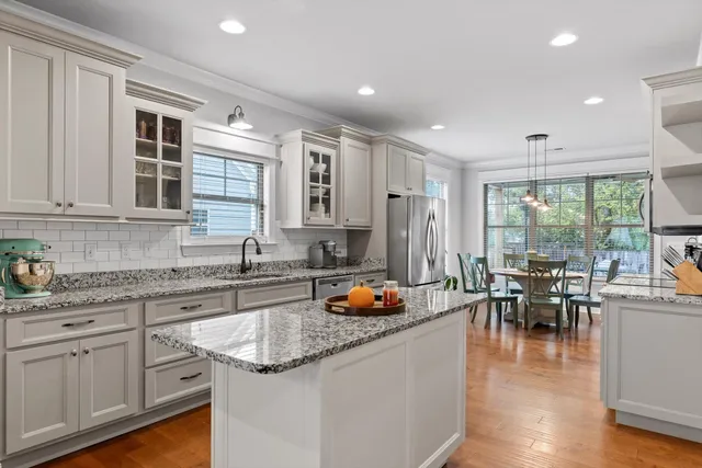 a kitchen with granite countertop lots of white cabinets and stainless steel appliances