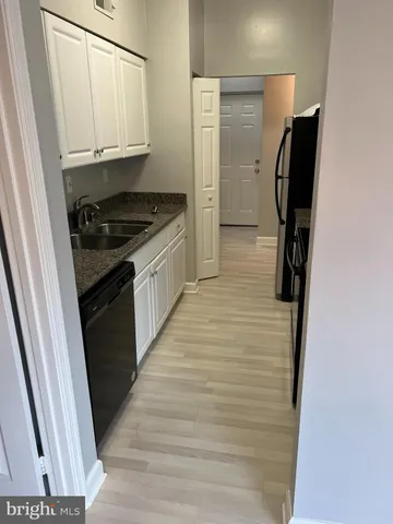 a kitchen with granite countertop white cabinets and refrigerator