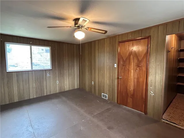 an empty room with windows closet and chandelier fan