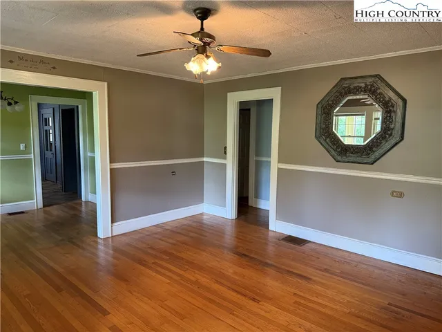 an empty room with wooden floor fan and windows