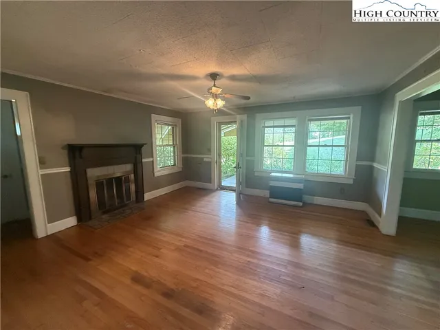 an empty room with wooden floor fireplace and windows