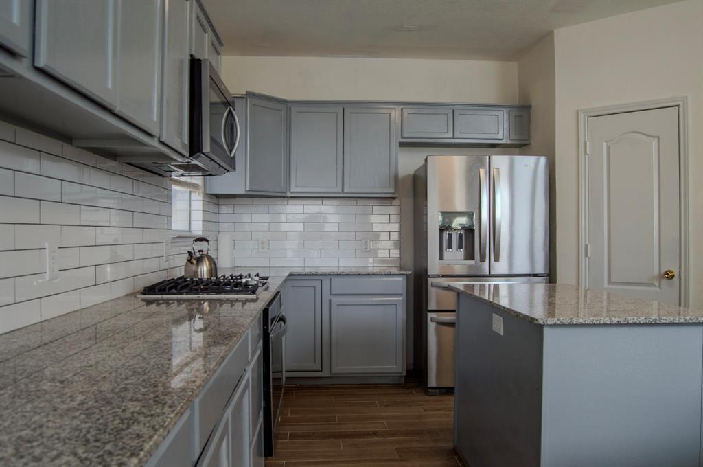 2700 Hereford Road Denton, TX 76210 - Photo 13 of 38 Kitchen featuring gray cabinets, stainless steel appliances, wood tiled floors, and light stone countertops