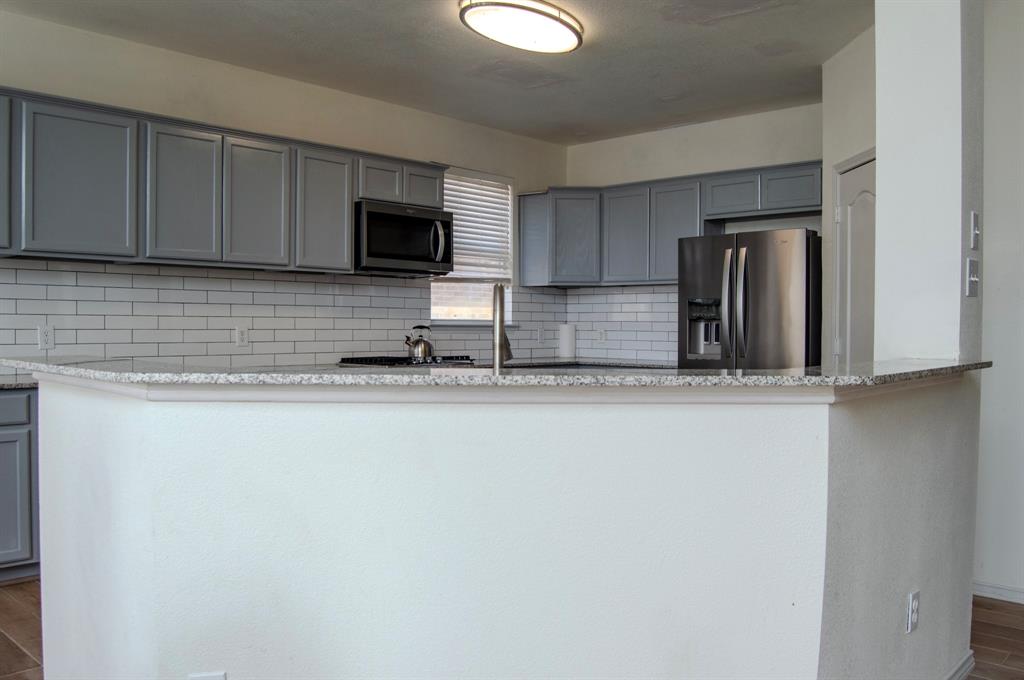 2700 Hereford Road Denton, TX 76210 - Photo 14 of 38 Kitchen with gray cabinets, dark wood-style floors, stainless steel appliances, light stone counters, and backsplash