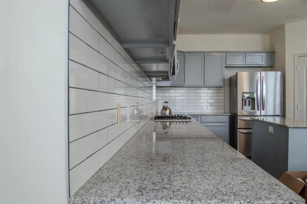 2700 Hereford Road Denton, TX 76210 - Photo 9 of 38 Kitchen featuring gray cabinets, light stone countertops, stainless steel appliances, and tasteful backsplash