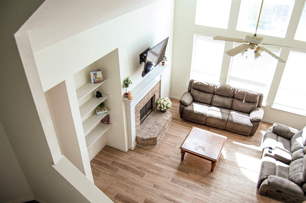 2700 Hereford Road Denton, TX 76210 - Photo 10 of 38 Living room featuring wood tiled floors, a high ceiling, a ceiling fan, a brick fireplace, and built in features