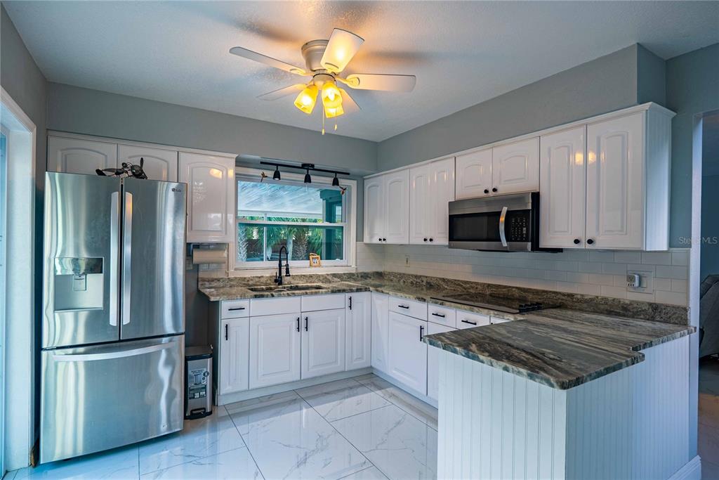 5124 Springwood Drive Tampa, FL 33624 - Photo 20 of 53 a kitchen with granite countertop a sink stainless steel appliances and white cabinets