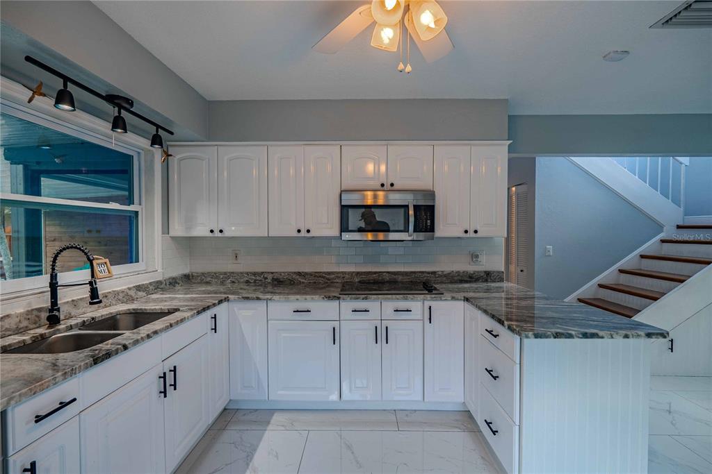 5124 Springwood Drive Tampa, FL 33624 - Photo 21 of 53 a kitchen with granite countertop a sink stainless steel appliances and white cabinets