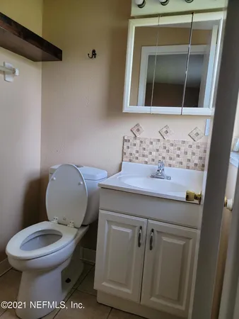 a bathroom with a toilet a sink and wooden floor