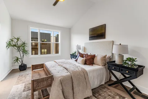 a bedroom with a bed a flat screen tv and a potted plant