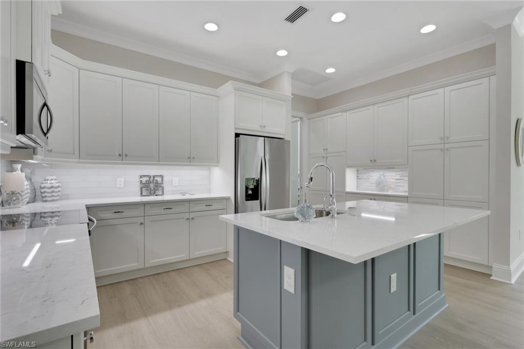 8861 Yucatan Court Naples, FL 34113 - Photo 8 of 39 a kitchen with a sink a stove a refrigerator and white cabinets