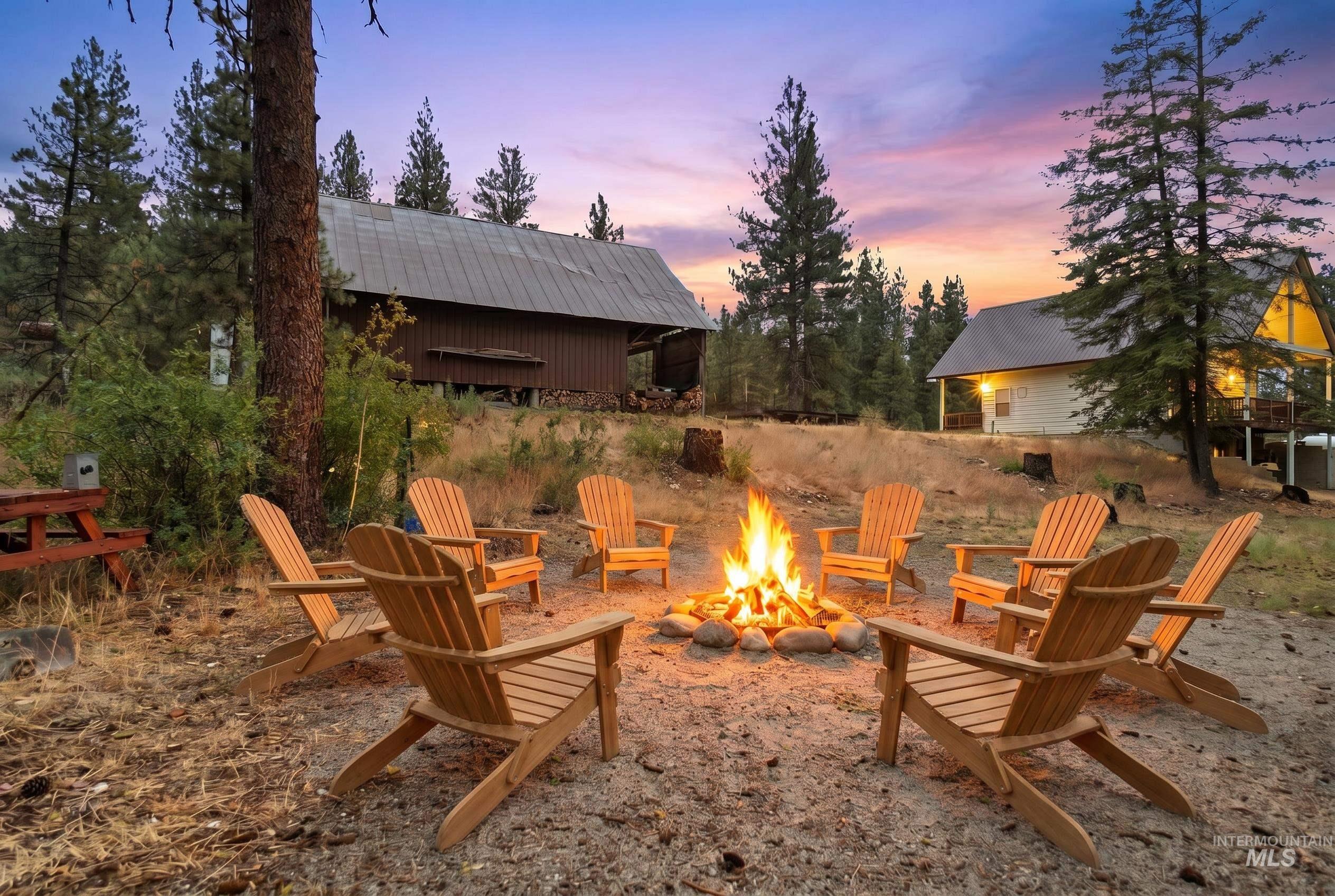 3980 North Pine-Featherville Road Mountain Home, ID 83647 - Photo 8 of 35 Outdoor fire pit surrounded by Adirondack chairs, set within a natural landscape