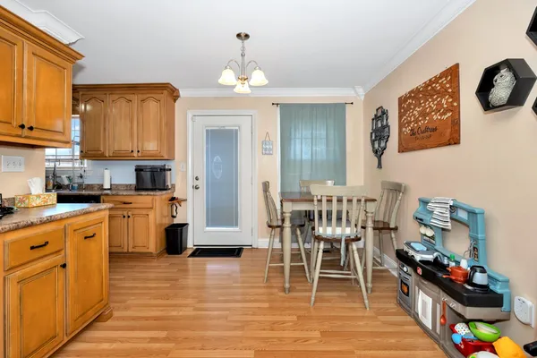 a kitchen with stainless steel appliances granite countertop a stove top oven a sink a dining table and chairs with wooden floor