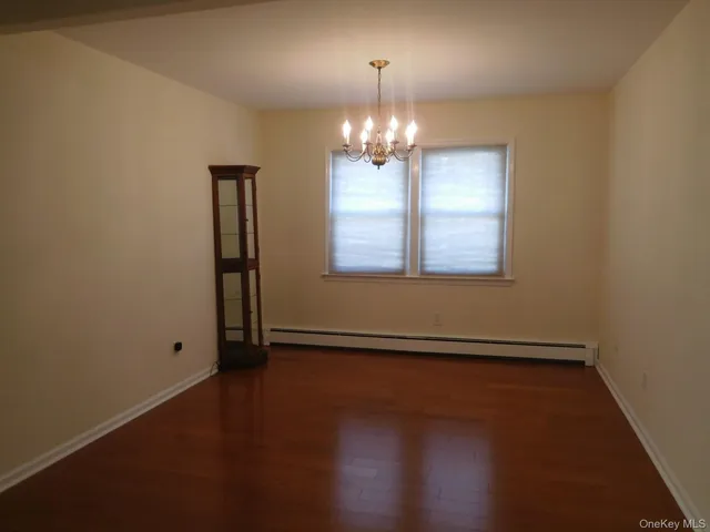 an empty room with wooden floor chandelier and windows