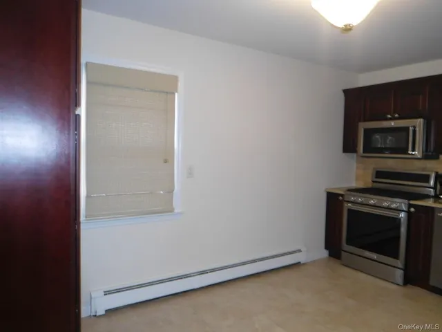 an empty room with a wooden floor and a kitchen
