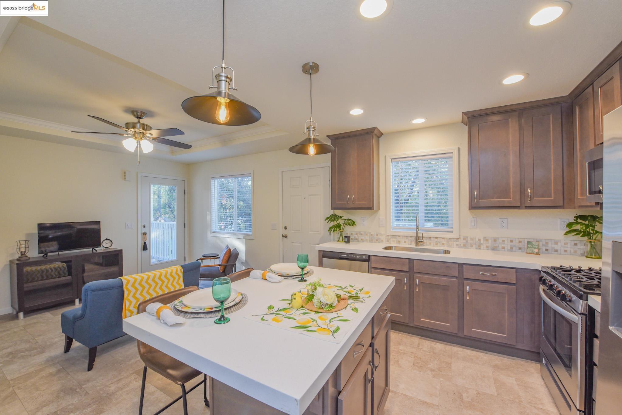 10956 Green Street Columbia, CA 95310 - Photo 43 of 45 Kitchen featuring appliances with stainless steel finishes, hanging light fixtures, open floor plan, dark brown cabinetry, and a center island