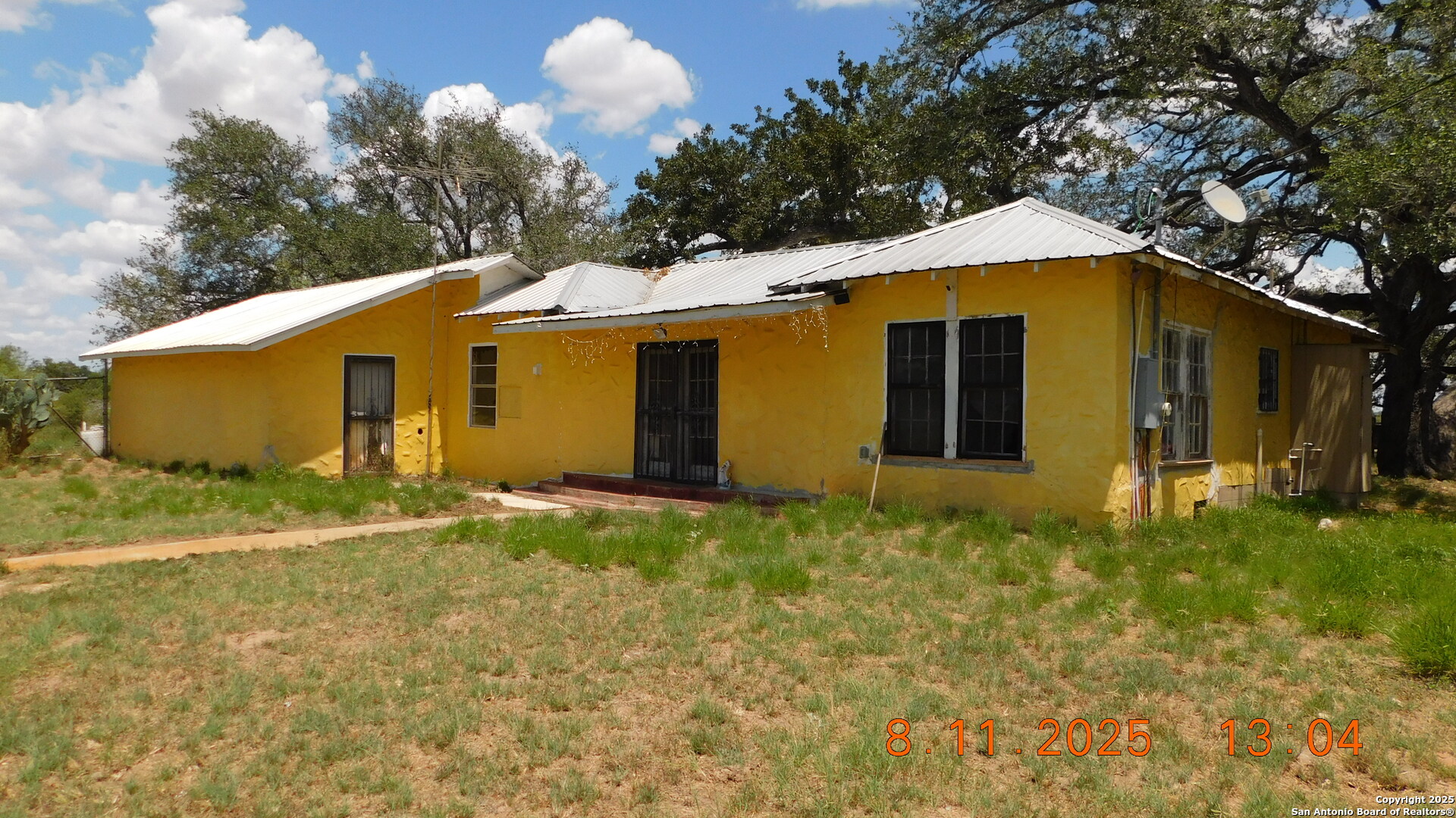 11620 Highway 16 Poteet, TX 78065 - Photo 2 of 38 a yellow house with a big yard and large trees