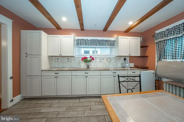 a kitchen with stainless steel appliances kitchen island granite countertop a table chairs sink and cabinets