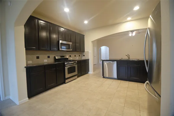 a large kitchen with granite countertop a large stove top oven and cabinets
