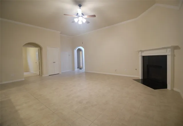 an empty room with a fireplace and chandelier fan