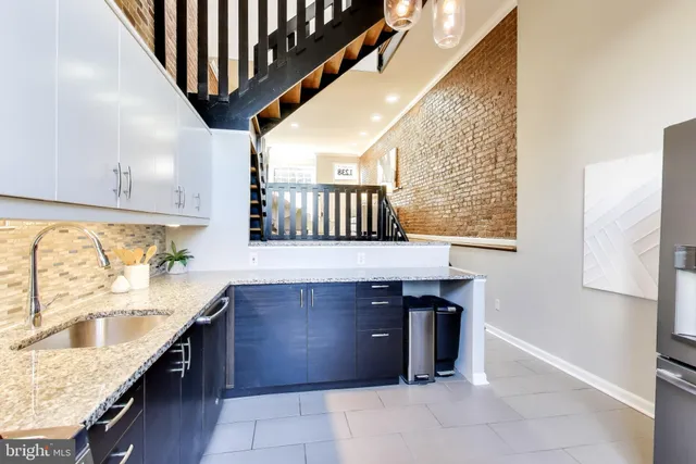 a kitchen with stainless steel appliances granite countertop a sink a stove and a wooden floors