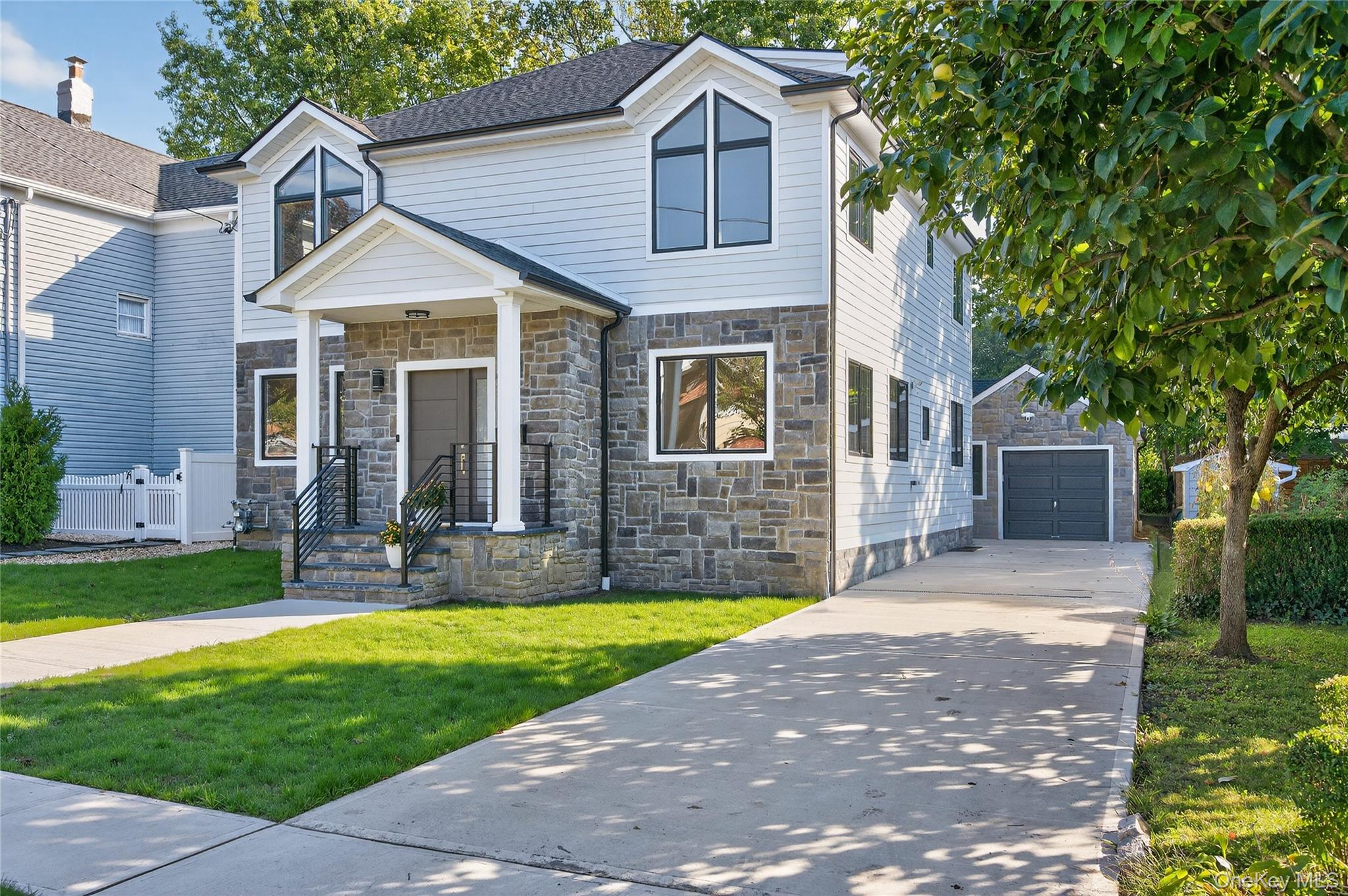 80 Clapham Avenue Manhasset, NY 11030 - Photo 31 of 31 View of front of home featuring stone siding, concrete driveway, an outdoor structure, and a garage