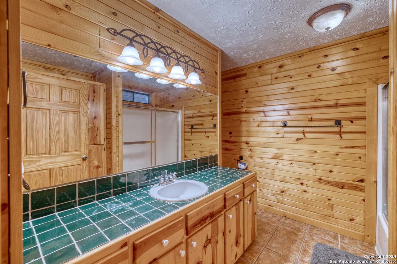 65 Comanche Crk Road Concan, TX 78838 - Photo 15 of 24 a bathroom with a granite countertop sink and a shower