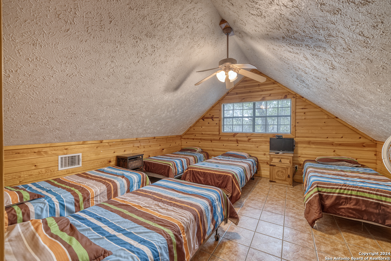 65 Comanche Crk Road Concan, TX 78838 - Photo 18 of 24 a bedroom with two beds and a chandelier