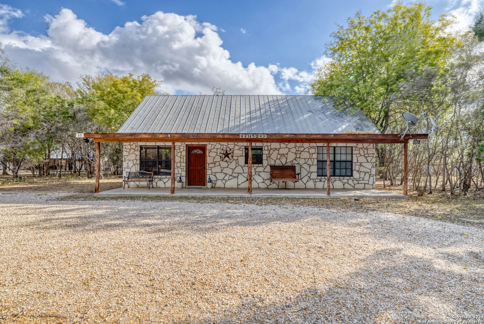 65 Comanche Crk Road Concan, TX 78838 - Photo 2 of 24 a front view of a house with a garden and patio