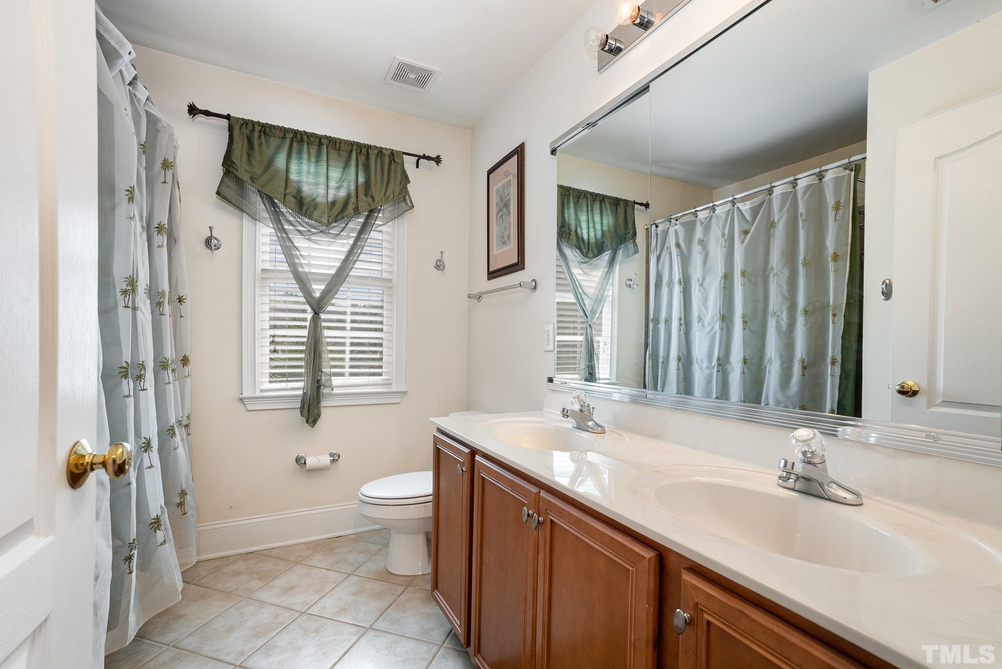 9300 Palm Bay Circle Raleigh, NC 27617 - Photo 21 of 30 a bathroom with double vanity sink a mirror a toilet and a window