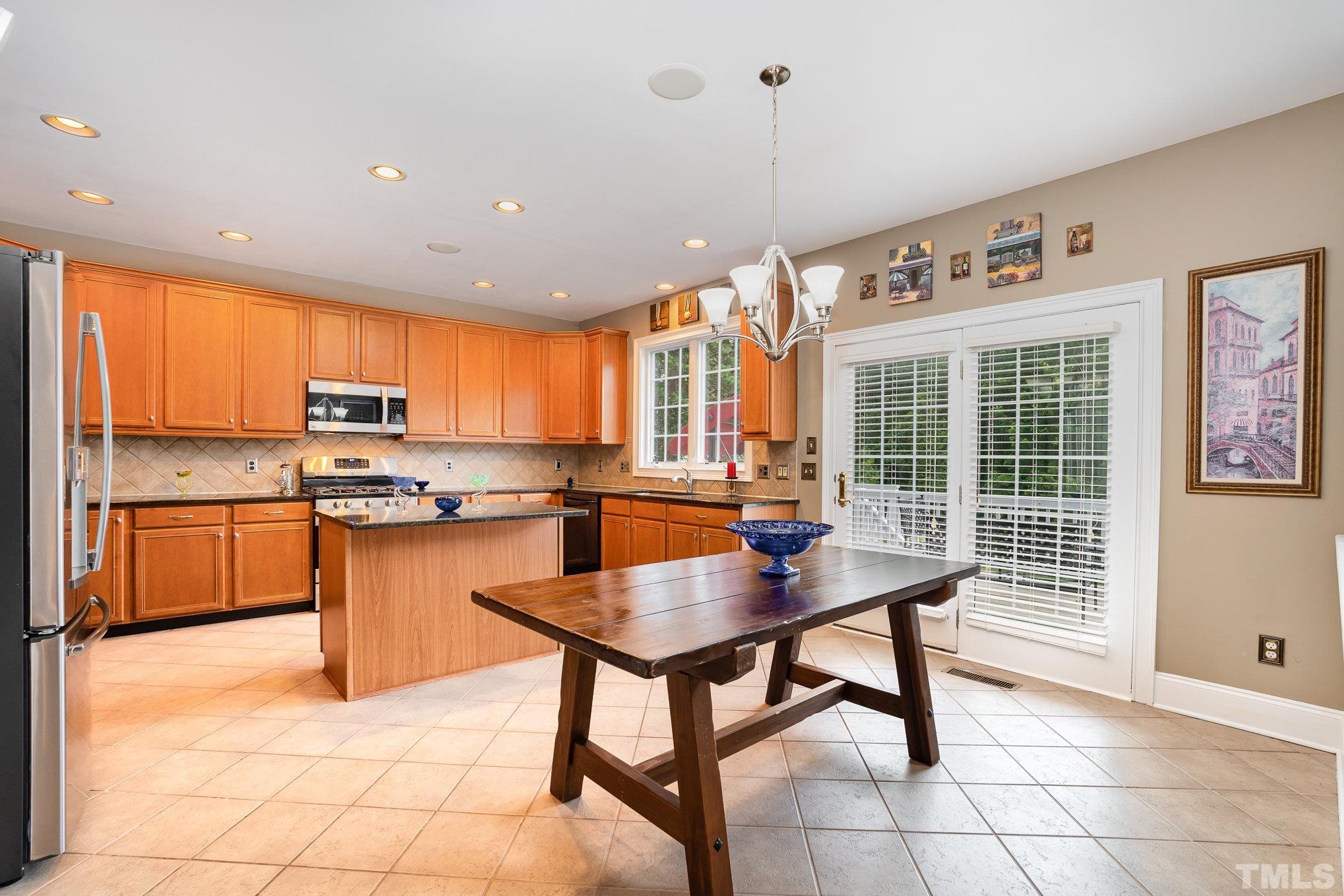 9300 Palm Bay Circle Raleigh, NC 27617 - Photo 9 of 30 a kitchen with stainless steel appliances granite countertop a stove top oven a sink dishwasher a dining table and chairs with wooden floor