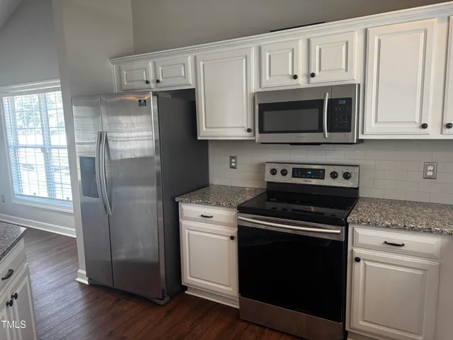 a kitchen with cabinets stainless steel appliances and wooden floor