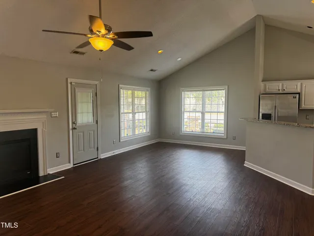 an empty room with wooden floor a ceiling fan and windows