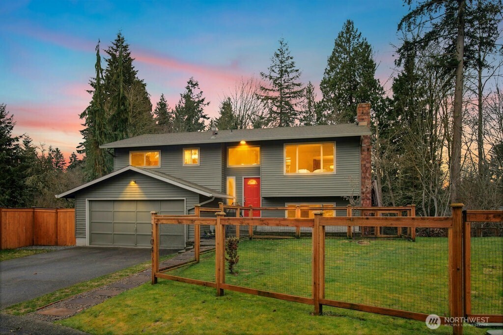 a view of a house with backyard and wooden fence