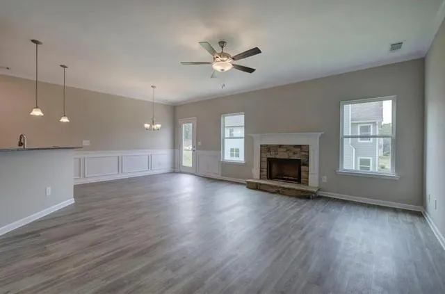 an empty room with wooden floor fireplace and windows