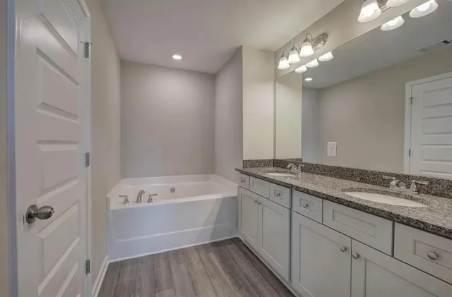 a bathroom with a tub a sink and mirror
