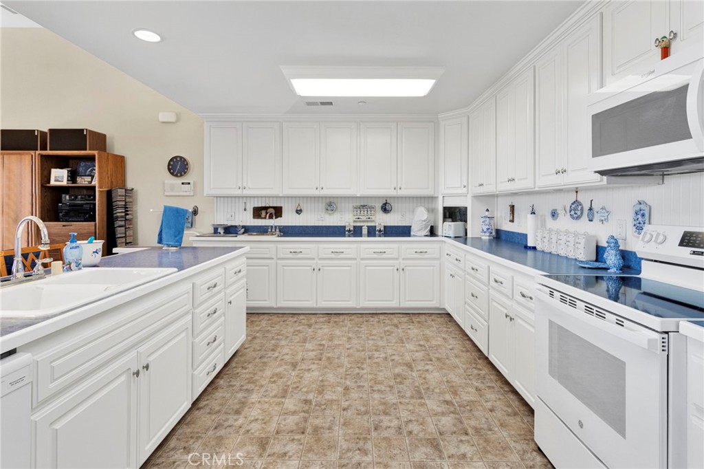 16222 Wild Road Helendale, CA 92342 - Photo 14 of 75 a large white kitchen with stainless steel appliances granite countertop a sink a stove top oven and white cabinets