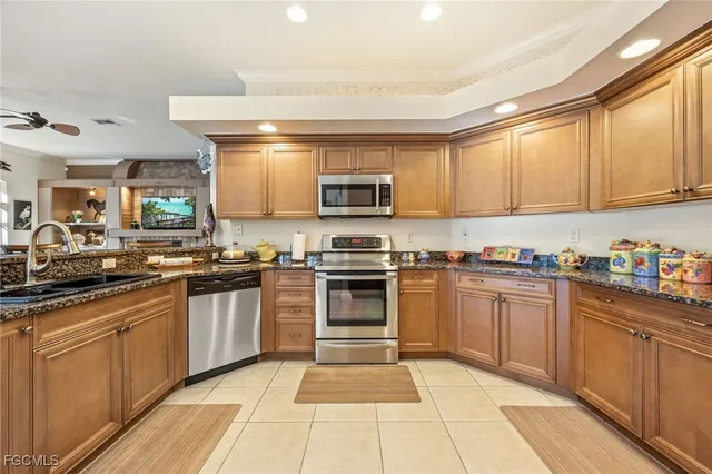 a kitchen with granite countertop a refrigerator a stove and white cabinets