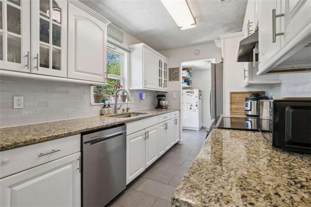 795 Tanner Road Dacula, GA 30019 - Photo 22 of 47 a large white kitchen with stainless steel appliances granite countertop a sink and dishwasher a stove with wooden floor
