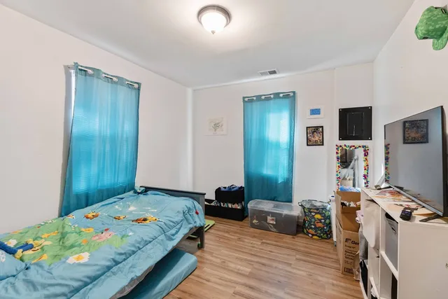 a bedroom with a bed and a flat tv screen on the dresser