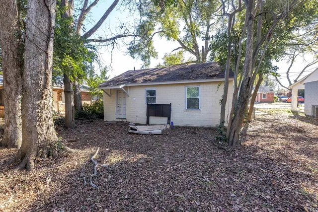 a view of a house with a yard and large tree