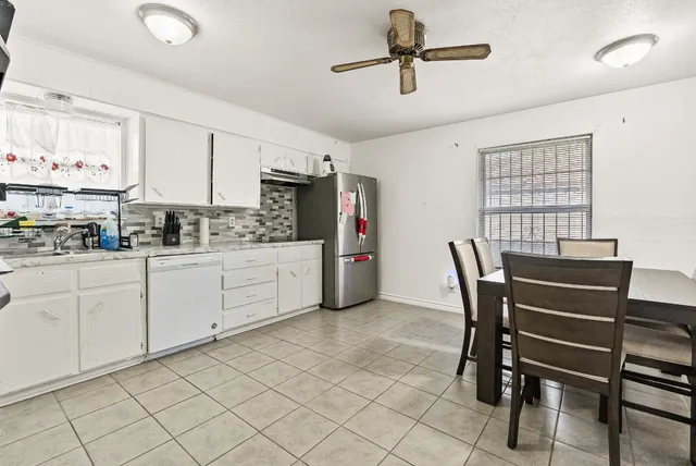 a kitchen with a dining table chairs and white cabinets