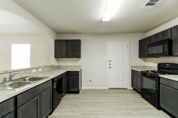 a kitchen with stainless steel appliances granite countertop a sink and a stove top oven with wooden floor