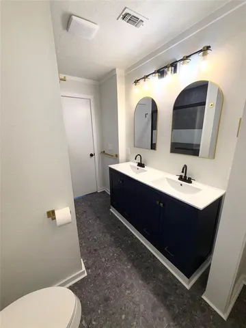 a bathroom with a double vanity sink toilet and mirror