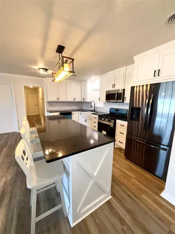a kitchen with kitchen island granite countertop a sink refrigerator stove and microwave