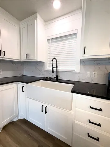 a kitchen with granite countertop white cabinets and sink