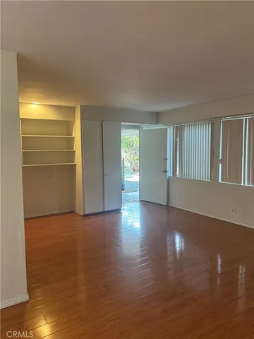 a view of an empty room with window and wooden floor