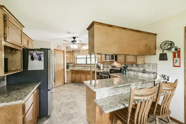 a kitchen with kitchen island granite countertop a sink cabinets and stainless steel appliances