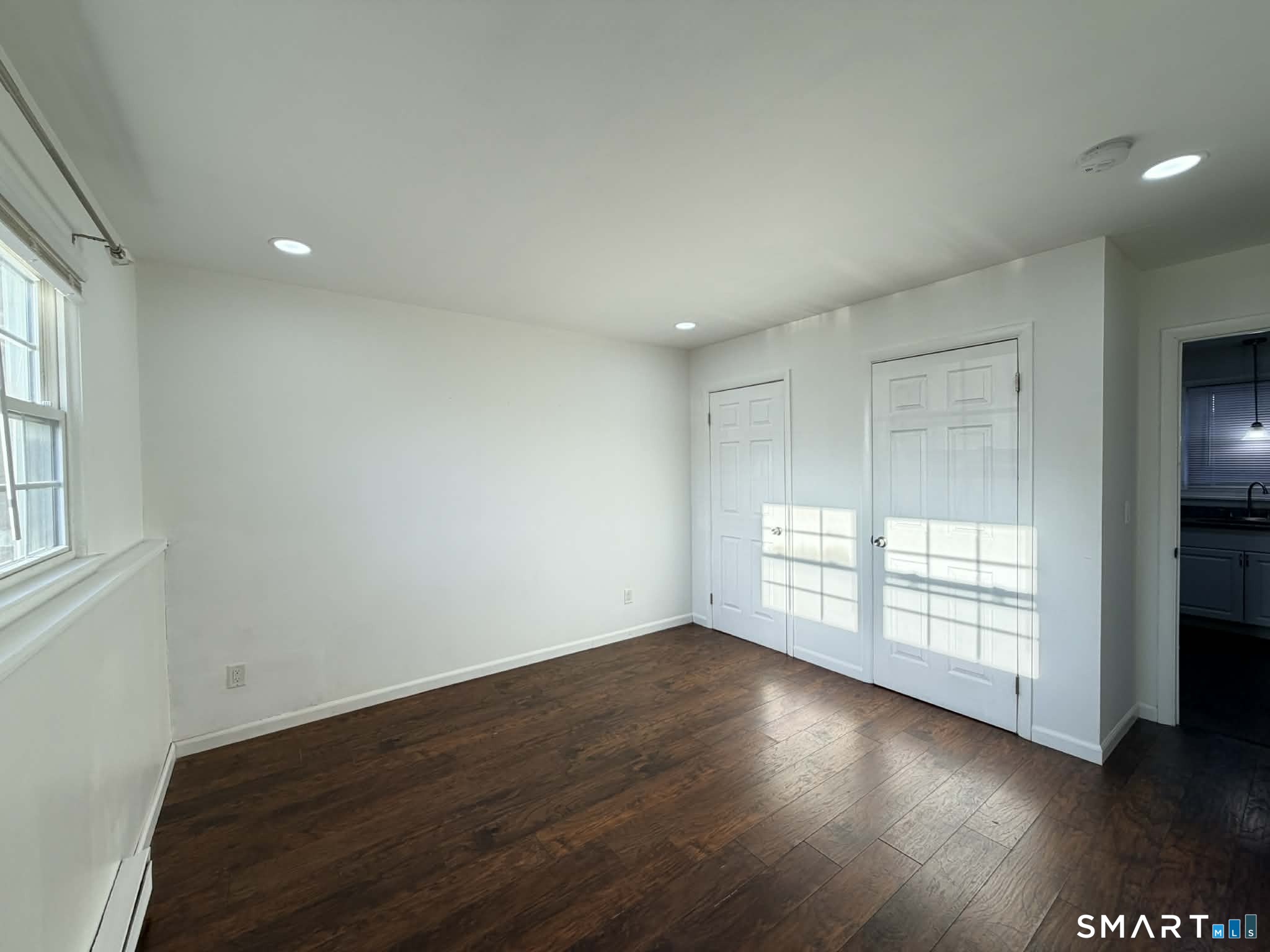 12 Terrace Place, Unit 2 New Milford, CT 06776 - Photo 9 of 11 an empty room with wooden floor and windows with curtains
